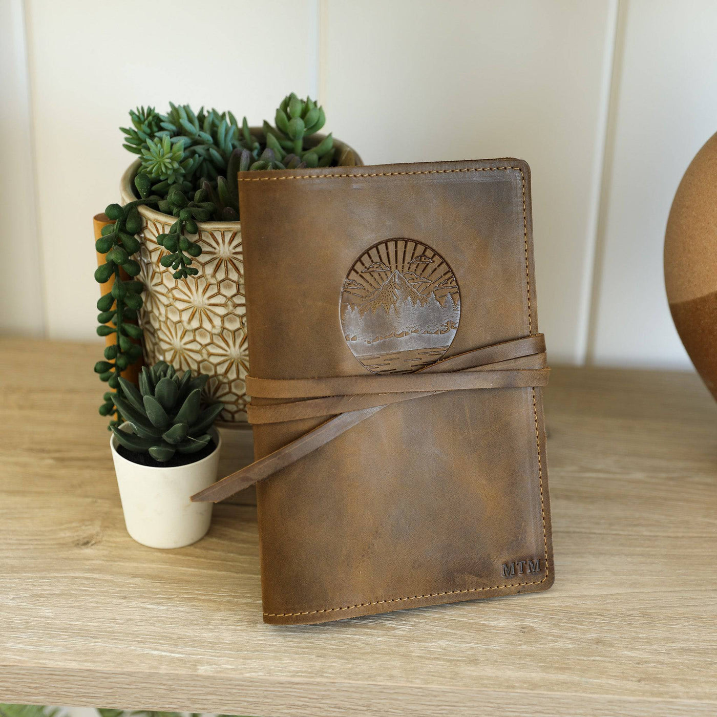 Closed desert sand brown leather journal resting on a wooden table.